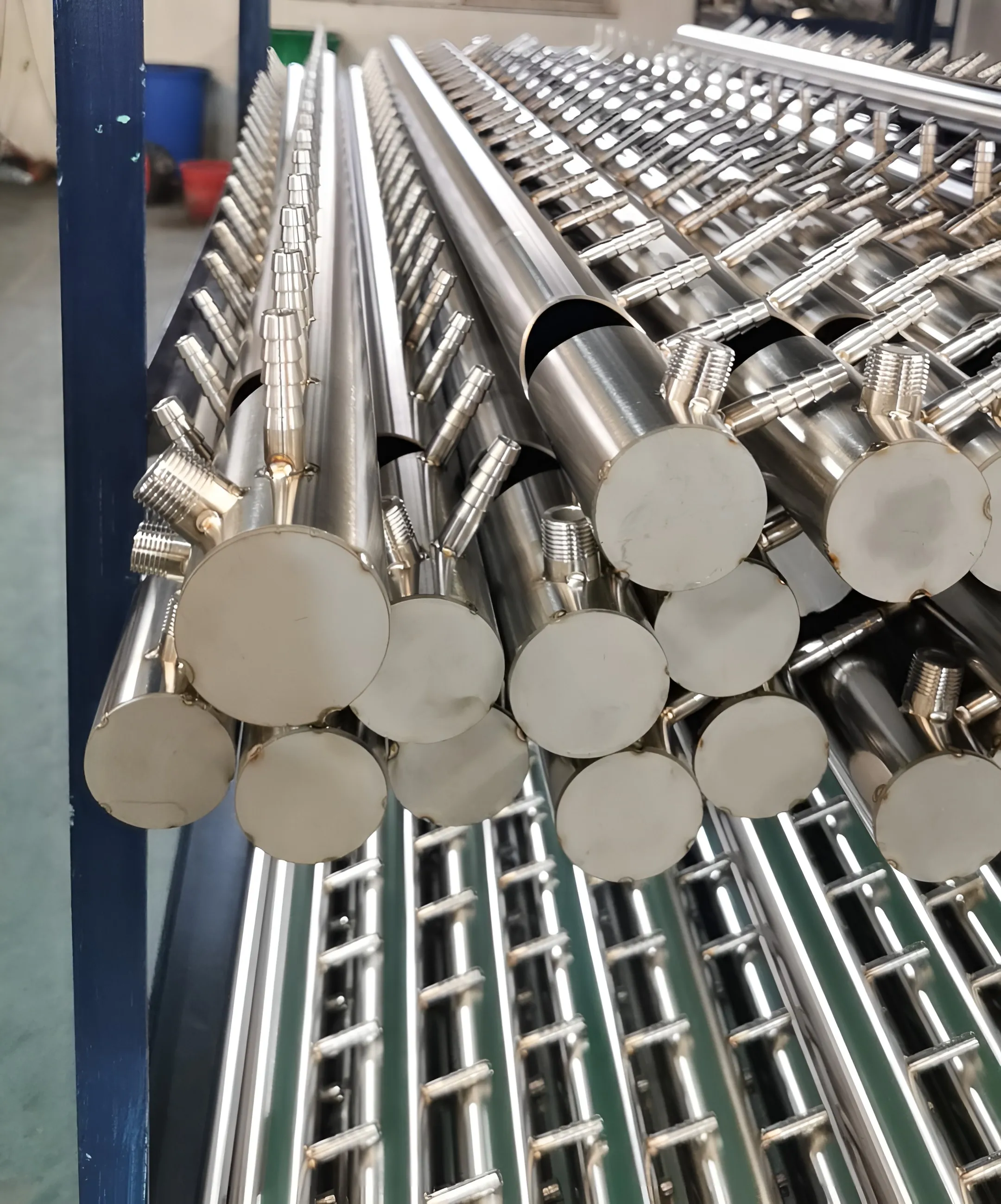 Stacked stainless-steel pipe sections with welded branch ports.